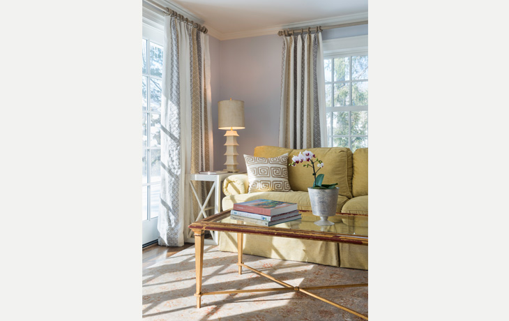 Bright sofa stands out against soft neutrals in a family room by Blue Jay Design of Wellesley, MA